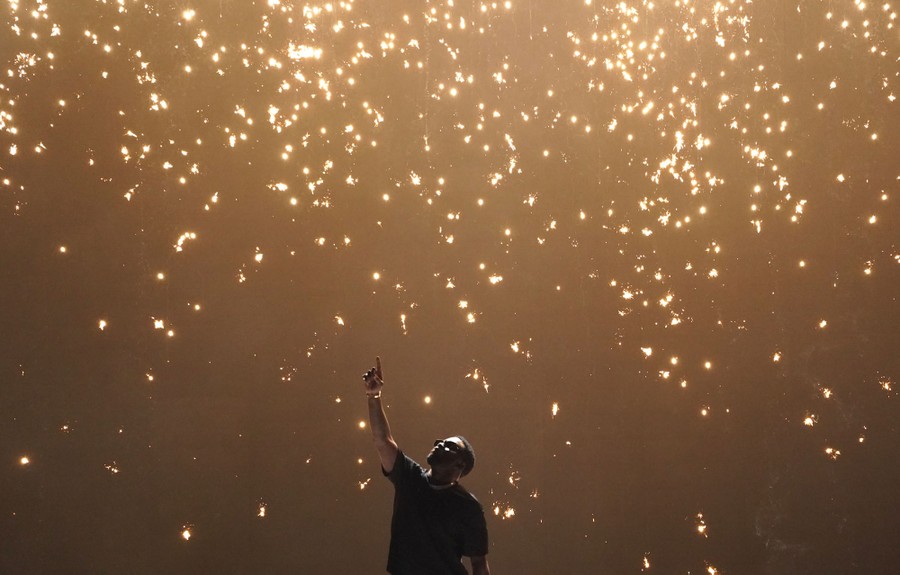 A performer points up as sparks fall from above.