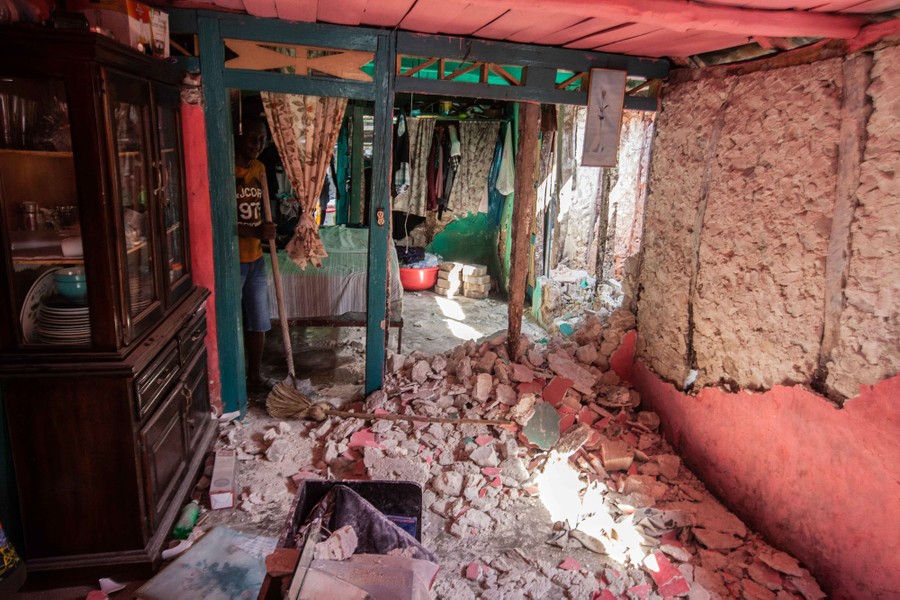 A person uses a shovel to clear rubble from inside their house