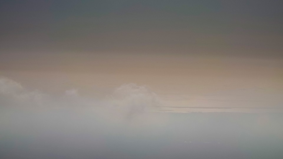 a cloudy beige sky, darker at the top of the image and lighter in the middle