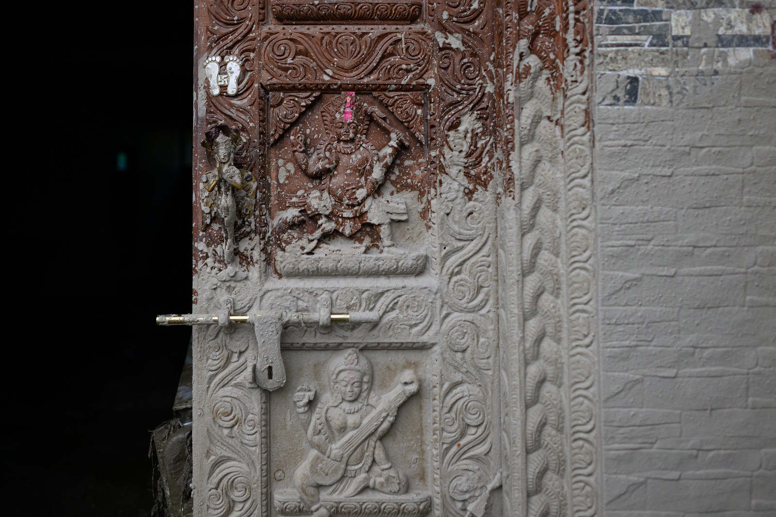 Splashed mud dries on the carved wooden door of a house.