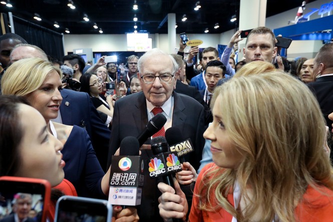 Buffett in the center of a crowd of members of the press.