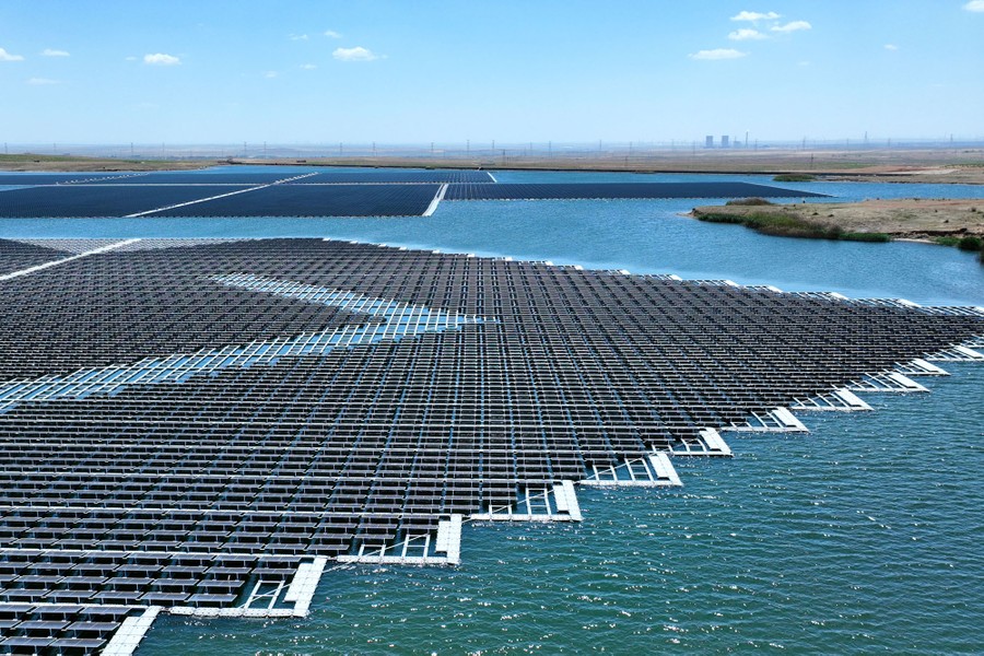 An aerial view of floating solar panels on the surface of a lake in a very flat landscape