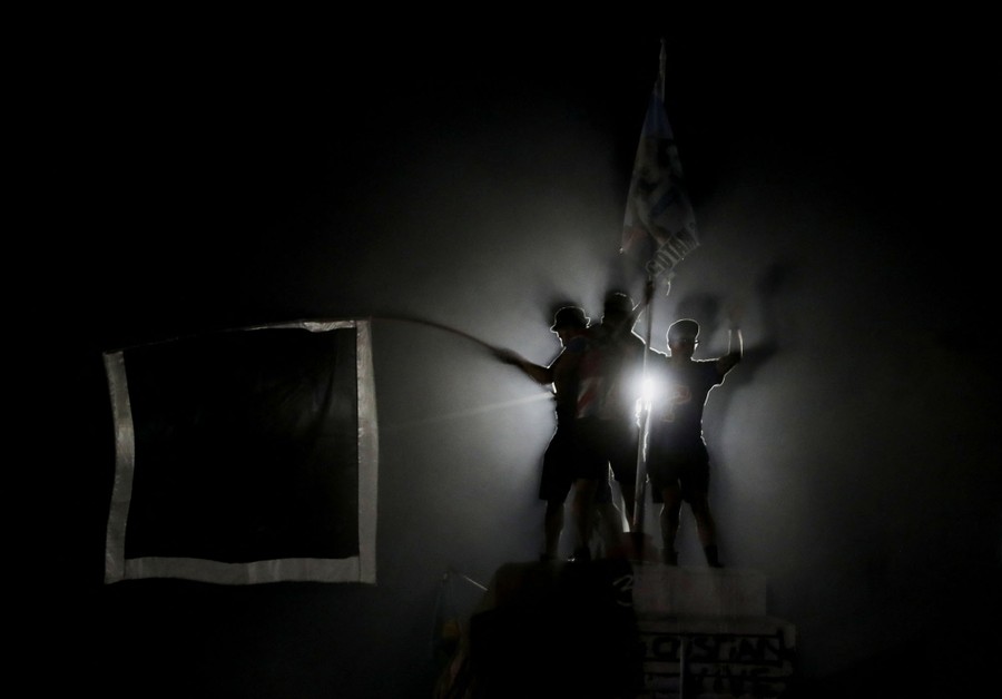 Several people are silhouetted while celebrating, standing on a pedestal.