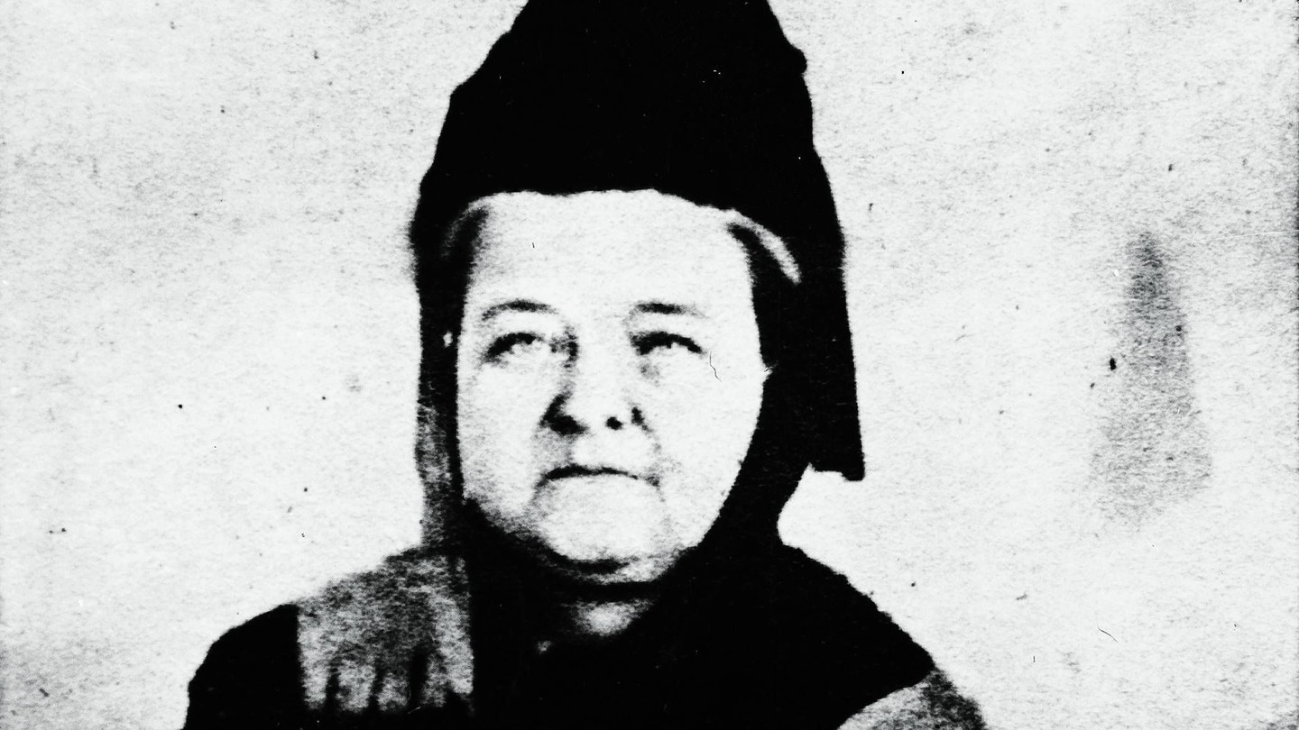A black-and-white image of Mary Todd Lincoln, with a ghost-like version of Abraham Lincoln to the right, standing and looking down towards her.