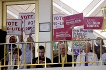 A photo of anti-abortion protesters holding up signs to the windows of a legislative assembly