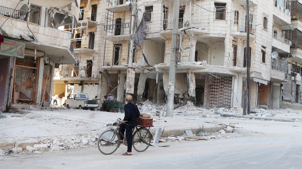 A man on a bicycle inspects a damaged building in eastern Aleppo in 2015.