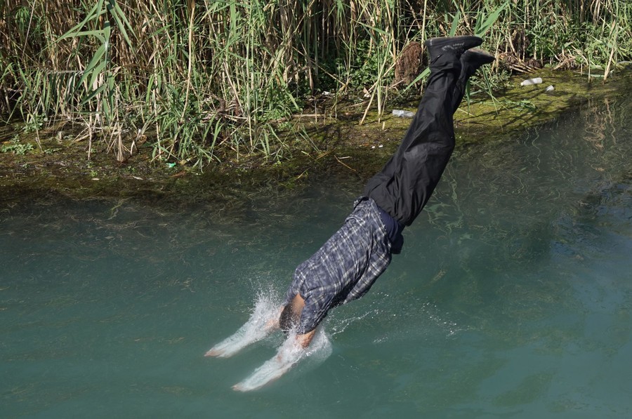 A person in mid-dive, jumping into water while fully clothed