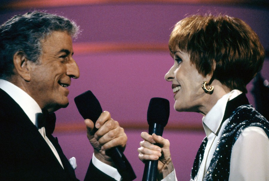 Tony Bennett and Carol Burnett sing while facing each other on a stage.