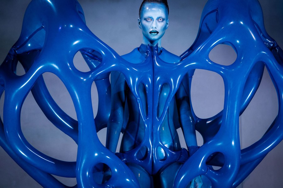 A model wears a complex blue garment that appears to be many inflatable latex tubes built into a kind of web.