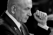 A side profile of Netanyahu with his fist at eye level and a mic near his mouth