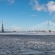 A huge bridge across an icy river, with smokestacks on both sides