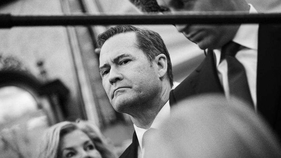 Michael Waltz looks on, beside Stephen Miller, in a black and white photo taken slightly at a tilt