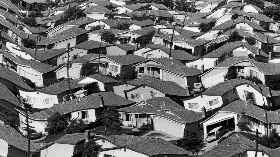 A warped black and white photograph of rows of houses in a neighborhood