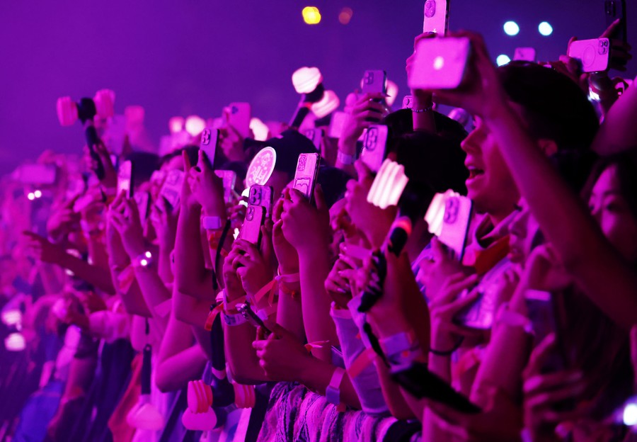 The front edge of a large crowd of festivalgoers. Most are holding phones up to take videos.