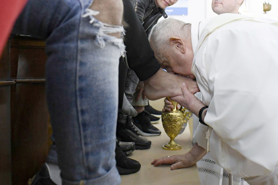 Pope Francis washes and kisses the feet of young people during a ceremony.