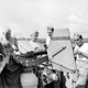 Young American soldiers in the South Pacific stand behind an anti-aircraft gun while eating ice cream, 1943