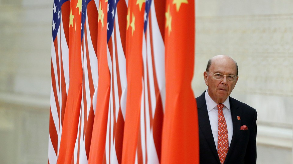 Commerce Secretary Wilbur Ross next to a series of flags