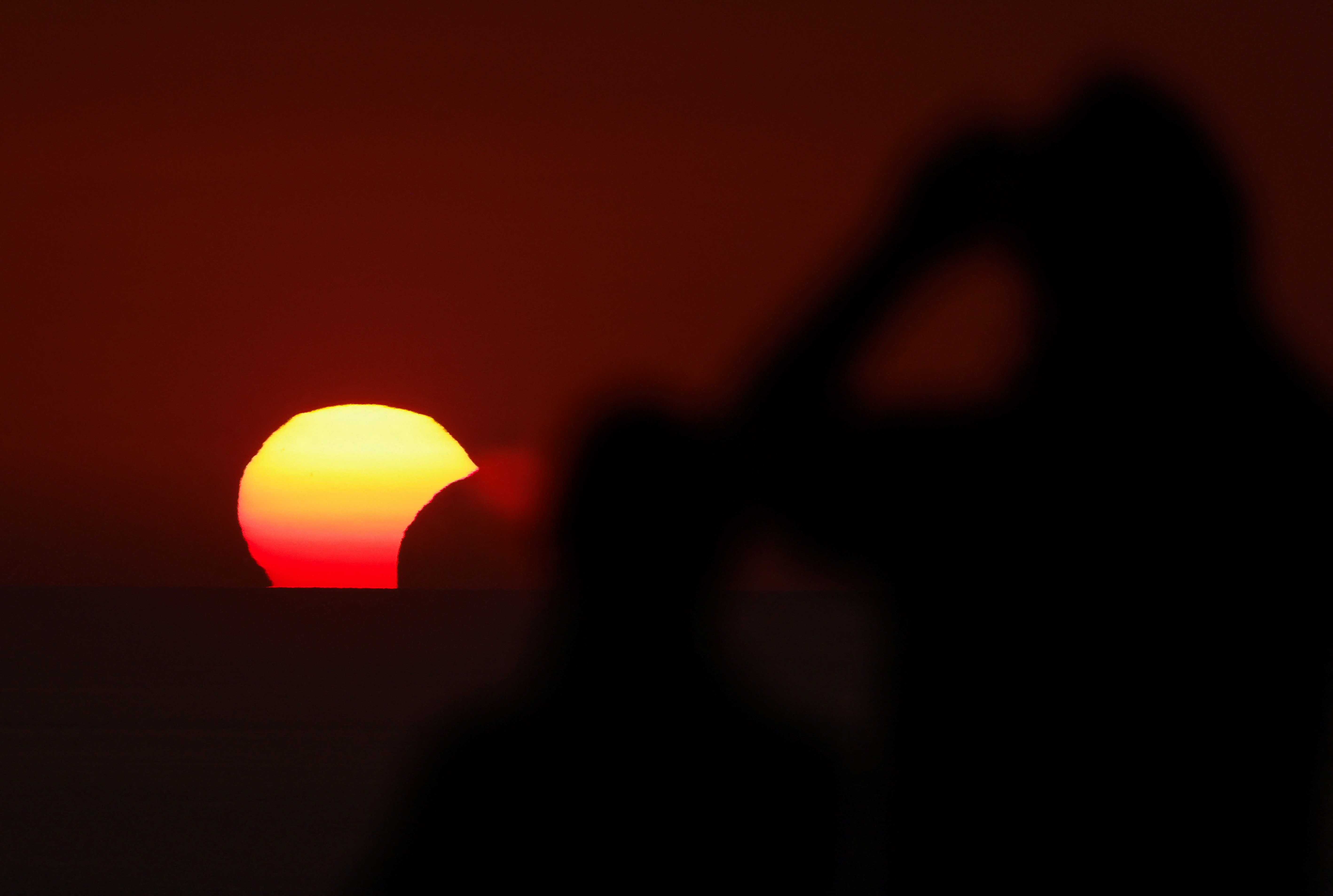 People watch a partial solar eclipse at sunset.