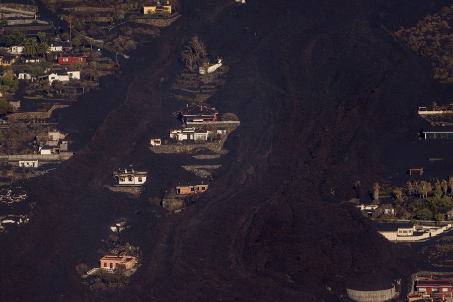 Lava flows among houses on a hillside.