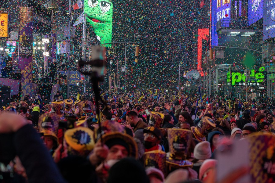 Hundreds of people celebrate in Times Square as confetti falls on them.