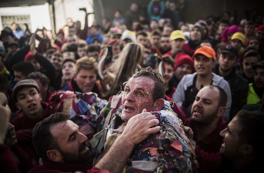 An exhausted man, covered in turnip debris, is hugged and celebrated by a mob.