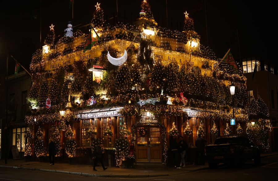 A pub adorned with many Christmas trees is seen lit up at night.