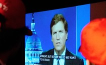 Two people in red caps watching Tucker Carlson's show