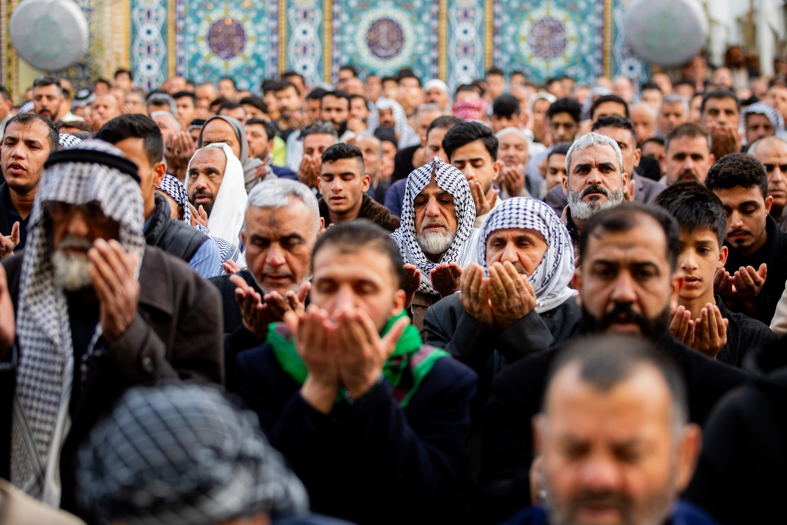 A group of Muslim men, praying outside a mosque.