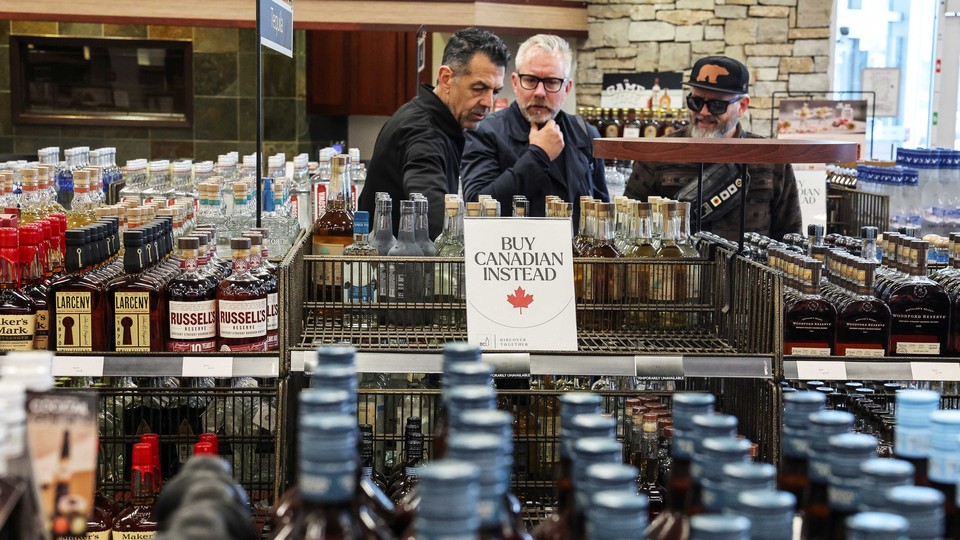 People look on as empty shelves remain with signs ''Buy Canadian Instead'' after the top five U.S. liquor brands were removed from sale at a B.C. Liquor Store