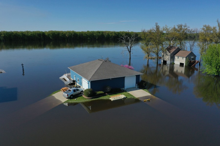 An aerial view of two homes surrounded by floodwater