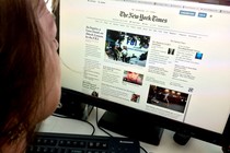 A woman reads The New York Times on her computer