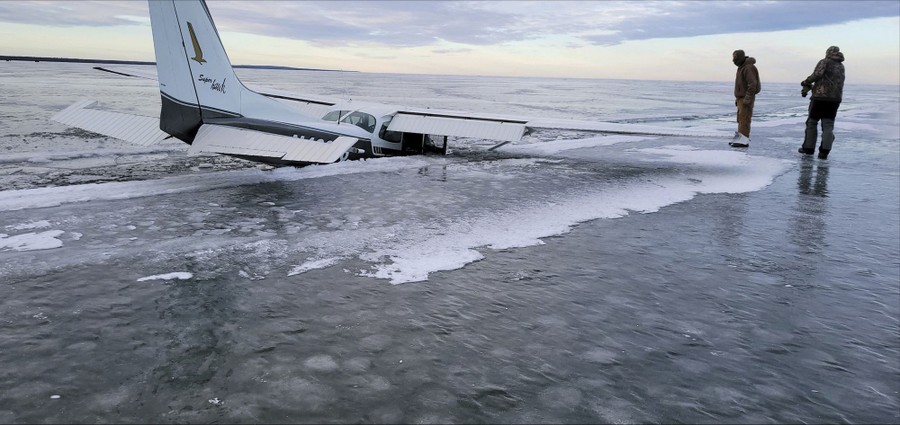 A small airplane sits half-submerged in a frozen lake.
