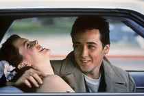 John Cusack and Ione Skye laugh together in a car.