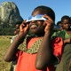 A girl looks through eclipse glasses.
