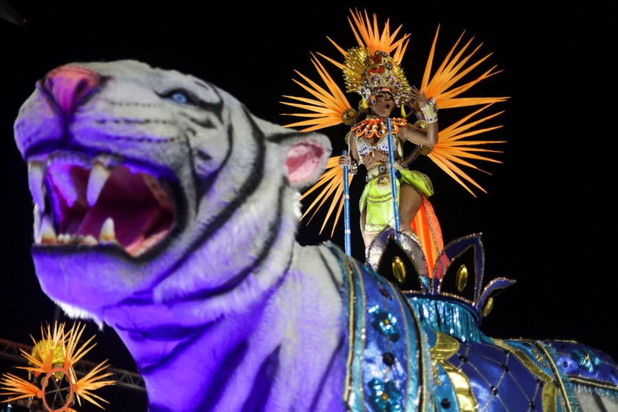 A dancer in an elaborate costume performs on a parade float.