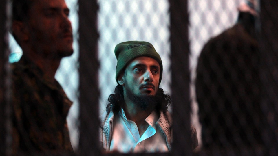 A suspected al-Qaeda militant stands behind bars. 