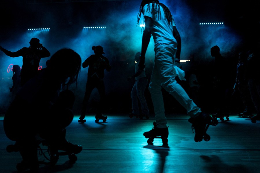 People enjoy themselves in a dimly lit indoor roller-skating rink.
