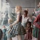 A young black girl and her mother look at a display case filled with white mannequins.