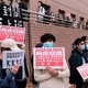 Medical workers in Hong Kong protest with red and white signs that say "Save HK now."