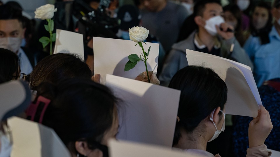 People holding white roses and white pieces of paper to protest China's zero-Covid restrictions in Hong Kong on November 28.