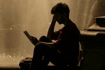 A boy reads a book in front of a fountain