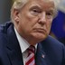 A close-up photo of President Trump in a meeting, wearing a navy suit and a red-and-blue tie