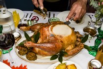 A man carves a Thanksgiving turkey on a dinner table