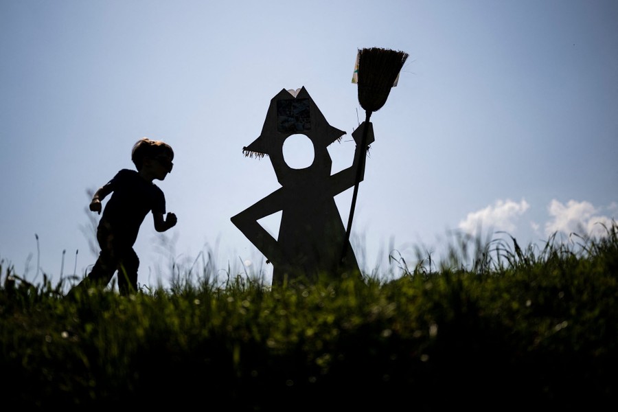A child runs near a scarecrow in a field.