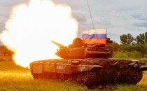 A Russian T-72 tank test-fires with a Russian flag atop it.