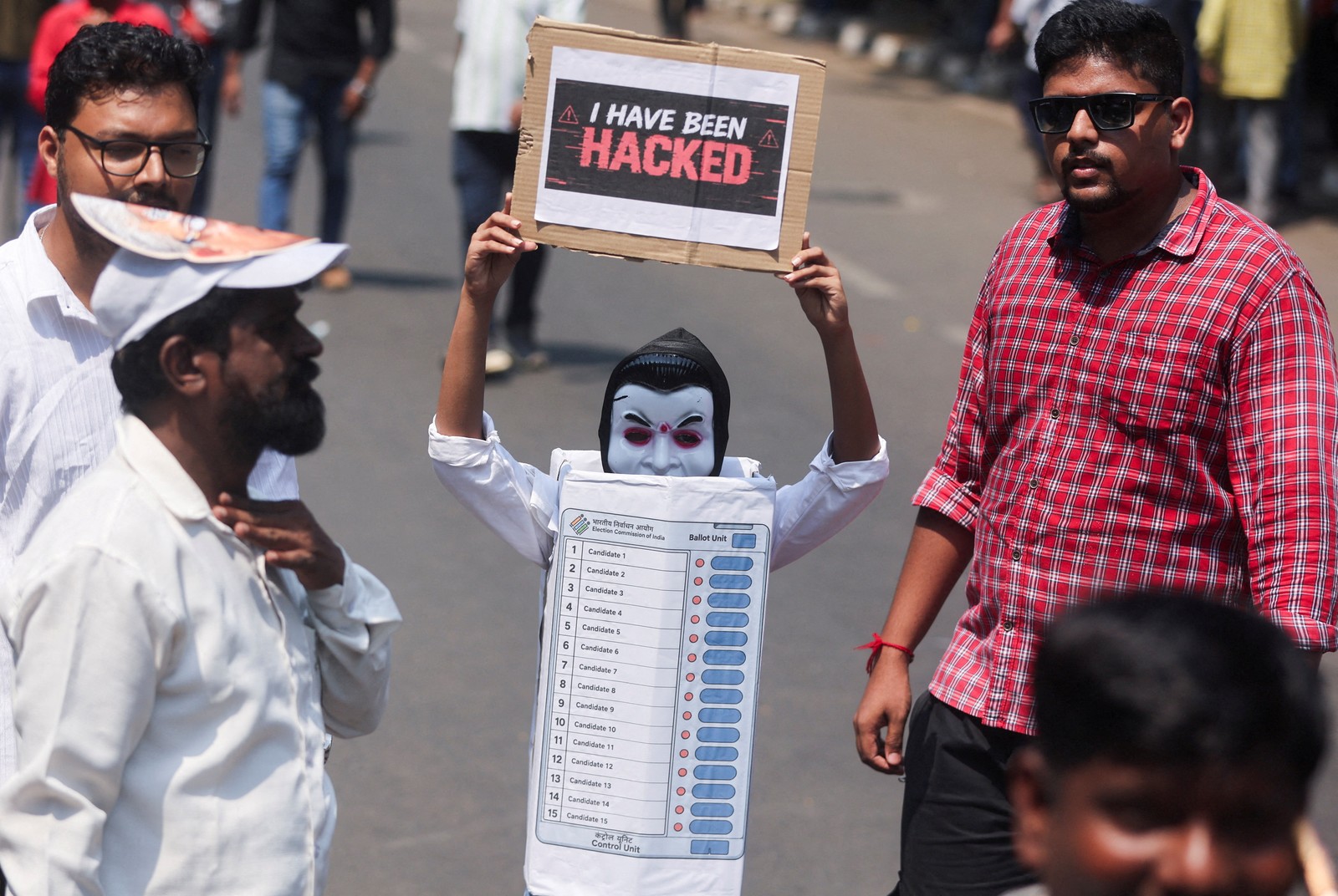A protester dressed as an electronic voting machine holds up a placard reading 'I have been hacked.'