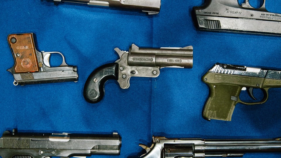 A photo of a row of handguns sitting on a blue tablecloth