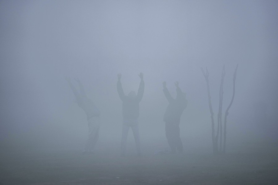 Three men stand together, arms up, on a foggy morning.