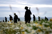A memorial made of life-sized silhouette cutouts of soldiers standing in a field of flowers