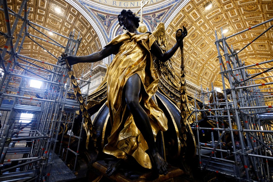 A close view of a gold statue, bronze curved ceilings, and scaffolding